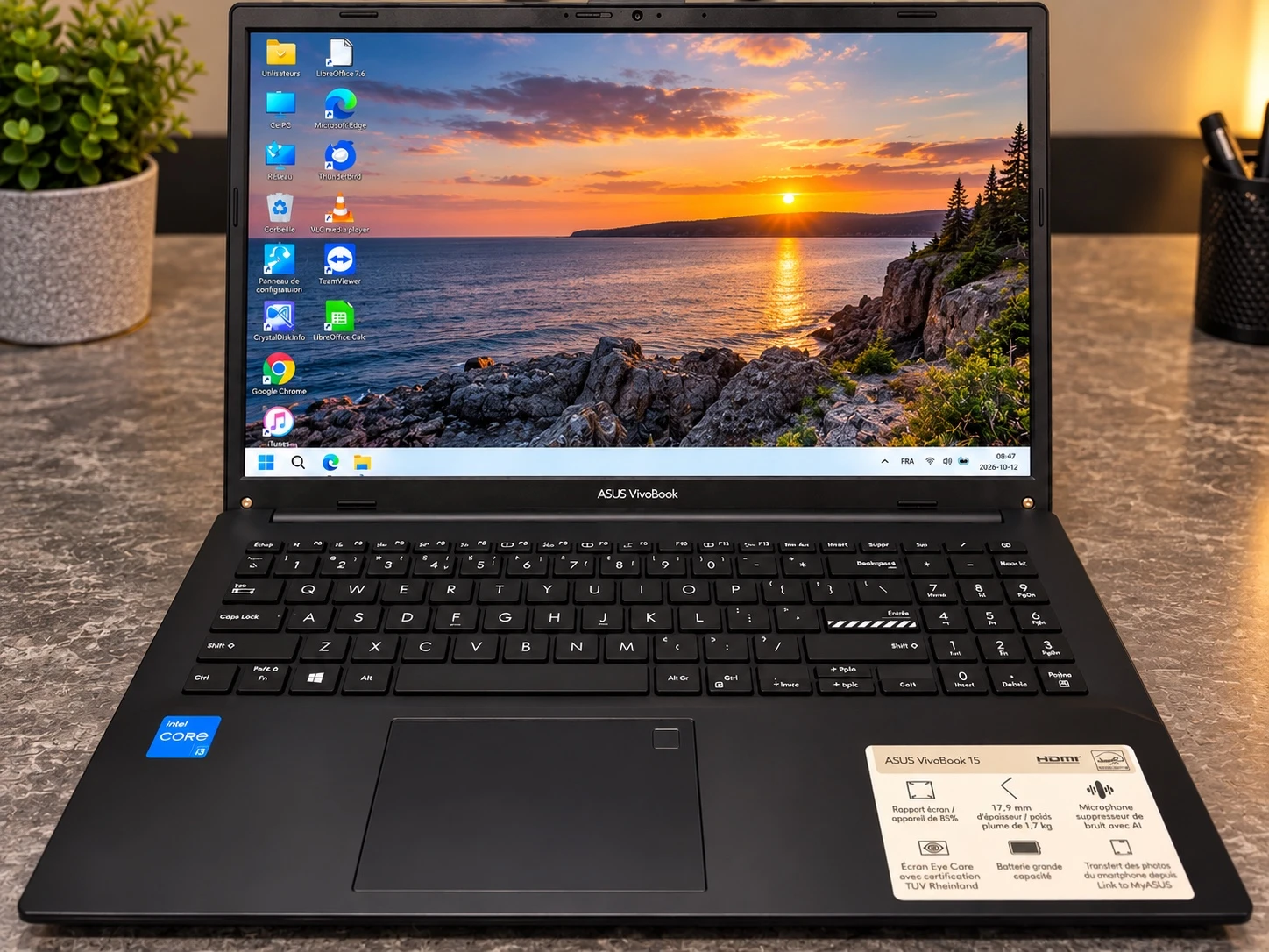 Ordinateur portable ASUS VivoBook 15 ouvert, avec un coucher de soleil en bord de mer à l’écran